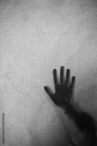 silueta de una mano en una cortina gris
