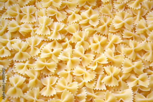 A lot of pasta in the shape of a butterfly on the table as a background.