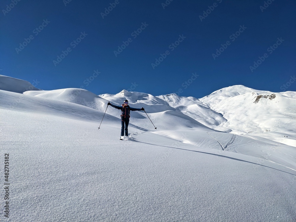 young woman enjoys the snow-covered mountain landscape with a deep snow descent in St. Antonien. Enjoy life. Skitouring