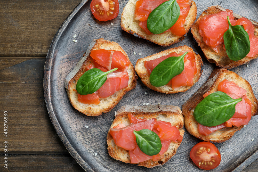 Delicious sandwiches with salmon and spinach on wooden table, top view Delicious sandwiches with salmon and spinach on wooden table, top view