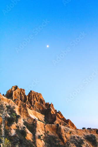 Blue hour near some beautiful cliffs with the moon in the sky © Bruno
