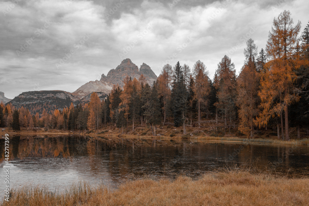 Reflection of autumnal larches on Lake Antorno, with the Tre Cime di Lavaredo in the background, Dolomites, Italy. Color isolation effect photo