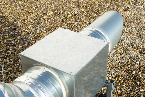 Air extractor and large galvanized steel pipes on the roof of a warehouse photo