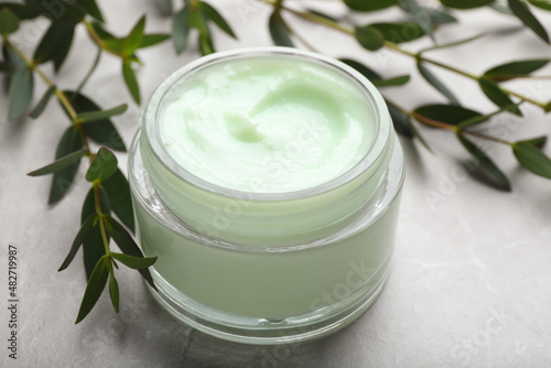 Jar of organic cream and eucalyptus on light table, closeup
