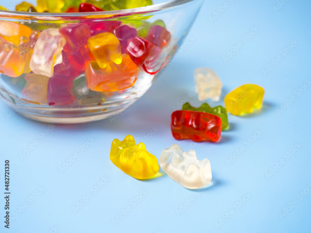 Bowl with tasty bright gummy bears on blue table Bowl with tasty bright gummy bears on blue table