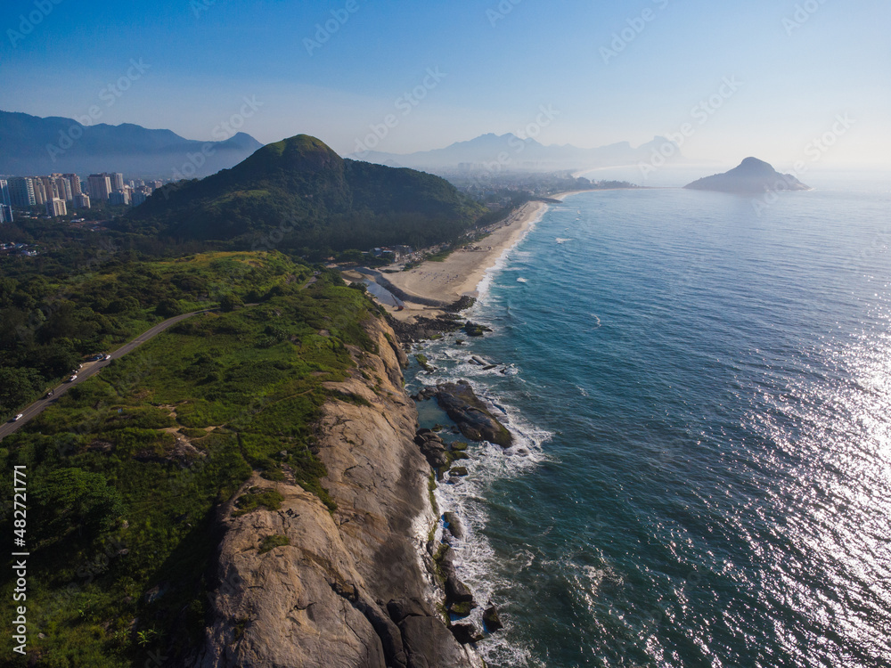 Aerial view of Praia do Secreto near Prainha beach, in Rio de Janeiro, Brazil. Big hills around. Sunny day at dawn. Recreio dos Bandeirantes in the background. Drone Photo