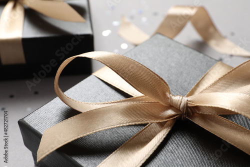 Beautiful gift box with bow on grey background, closeup view photo