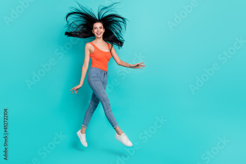 Photo of charming shiny woman wear red singlet jumping high walking empty space isolated teal color background