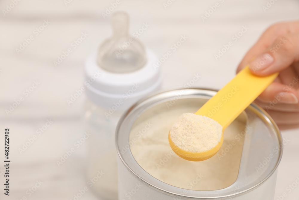 Woman with powdered infant formula at table, closeup and space for text. Preparing baby milk Woman with powdered infant formula at table, closeup and space for text. Preparing baby milk