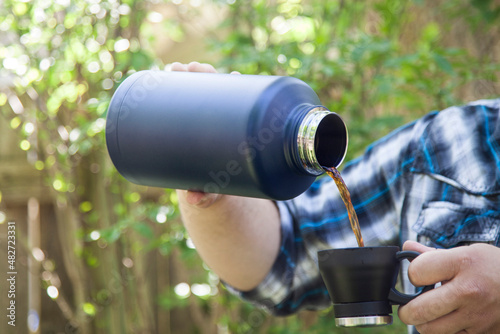 Man pours coffee from thermos into cup