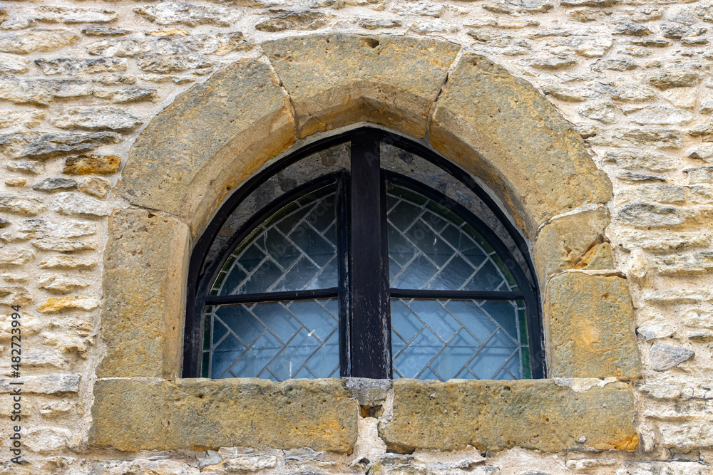 A window with decorative glass in the facade of a historic building.