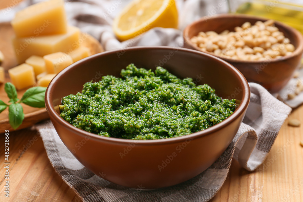 Bowl of tasty pesto sauce and ingredients on wooden background Bowl of tasty pesto sauce and ingredients on wooden background
