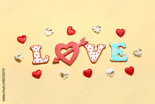 Word LOVE and different heart shaped cookies on color background