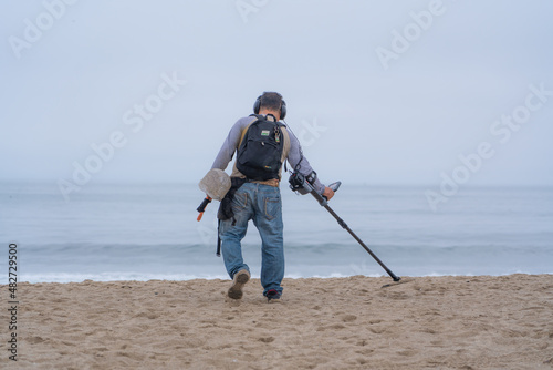 Man with a metal detector looking for treasure on a beach