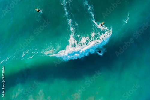 Surfer ride on surfboard on blue wave in ocean. Aerial view in Brazil