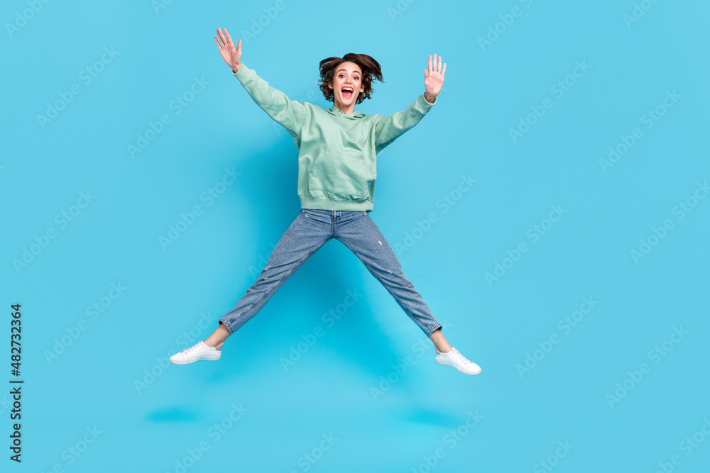 Full length photo of impressed millennial brunette lady jump wave wear pullover jeans footwear isolated on blue background