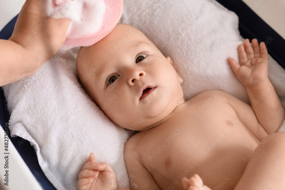 Mother washing her baby boy with sponge at home, closeup Mother washing her baby boy with sponge at home, closeup