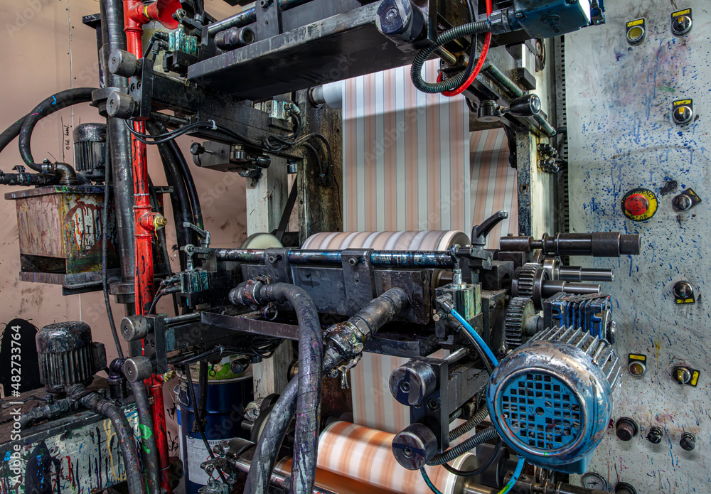Rotary die cutting machine with slitting blade system. Production of duct tape.Packing tape manufacturing, CMYK in print manufacturing.  Industrial and technology concept.