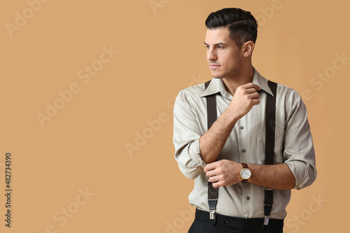 Fashionable gentleman adjusting sleeve on color background