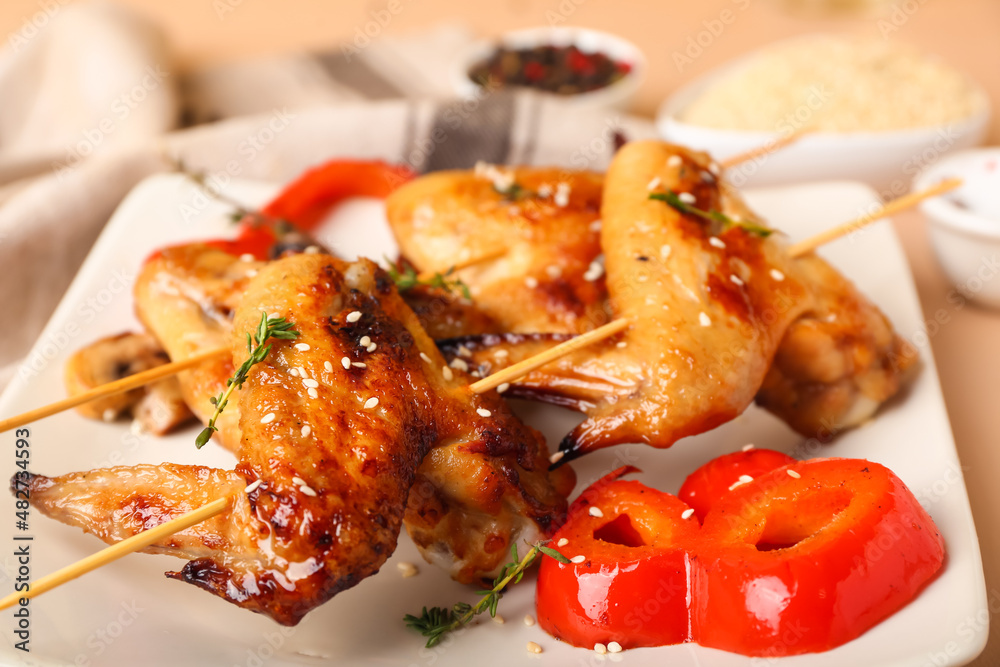 Plate with grilled chicken wings skewers on beige background, closeup Plate with grilled chicken wings skewers on beige background, closeup