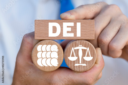 Concept of DEI Diversity Equality Inclusion. Multiracial Multicultural Community. Man holding wooden blocks with abbreviation a DEI - Diversity Equity Inclusion Belonging Human Rights. photo