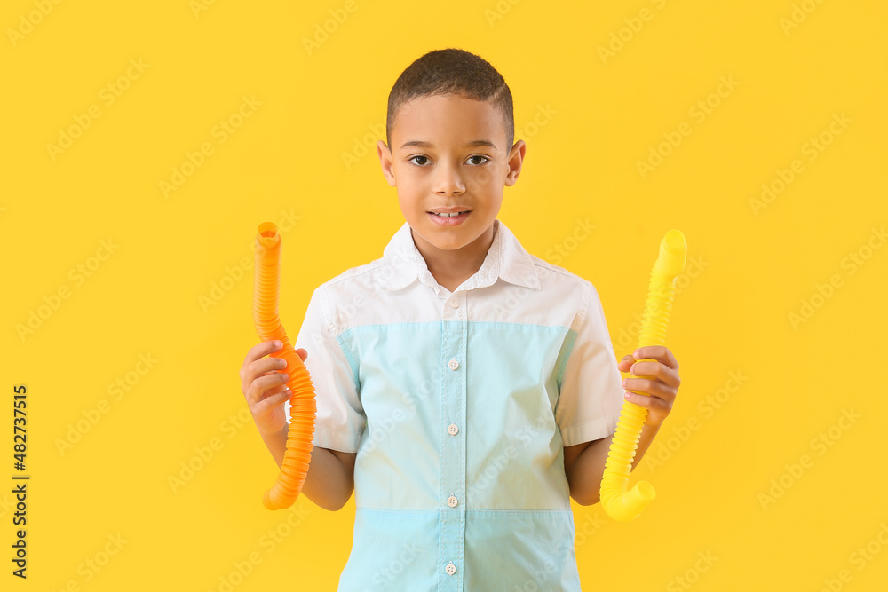 Little African-American boy with Pop Tubes on yellow background Little African-American boy with Pop Tubes on yellow background