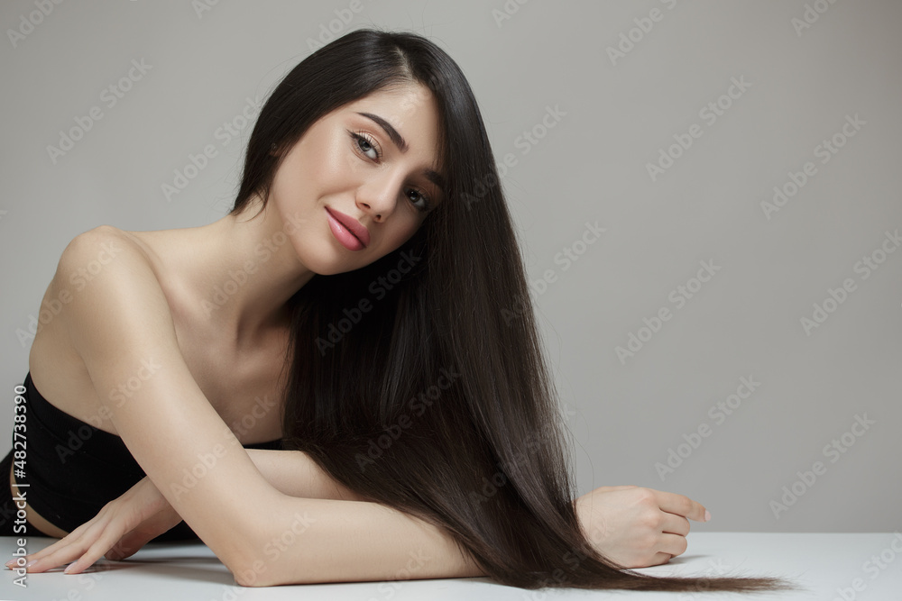 Beautiful young brunette woman with long straight hair sits at the ...