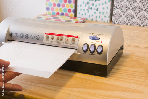 Photos Mature Man using thermal plasticizing machine, laminate credentials in the offic
