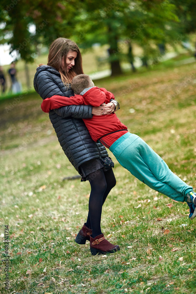 Mum hugging his son, spinning around in the park, having fun, loving each other Mum hugging his son, spinning around in the park, having fun, loving each other