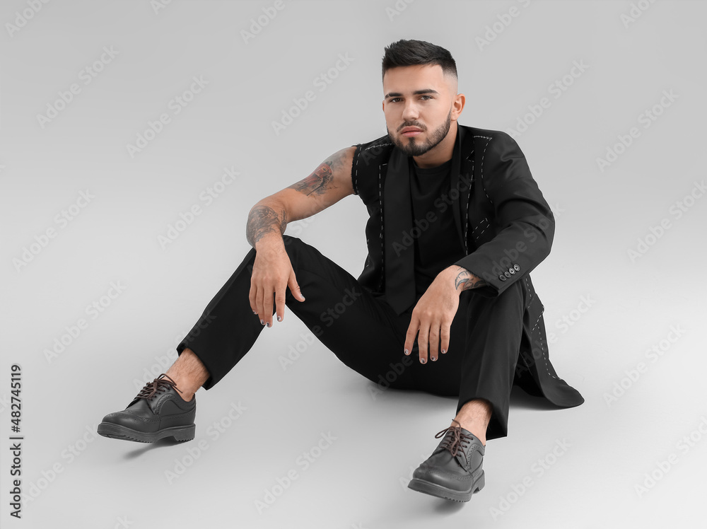 Young man with stylish manicure in unfinished suit on light background Young man with stylish manicure in unfinished suit on light background