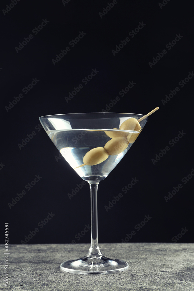 Martini cocktail with olives on grey table against dark background