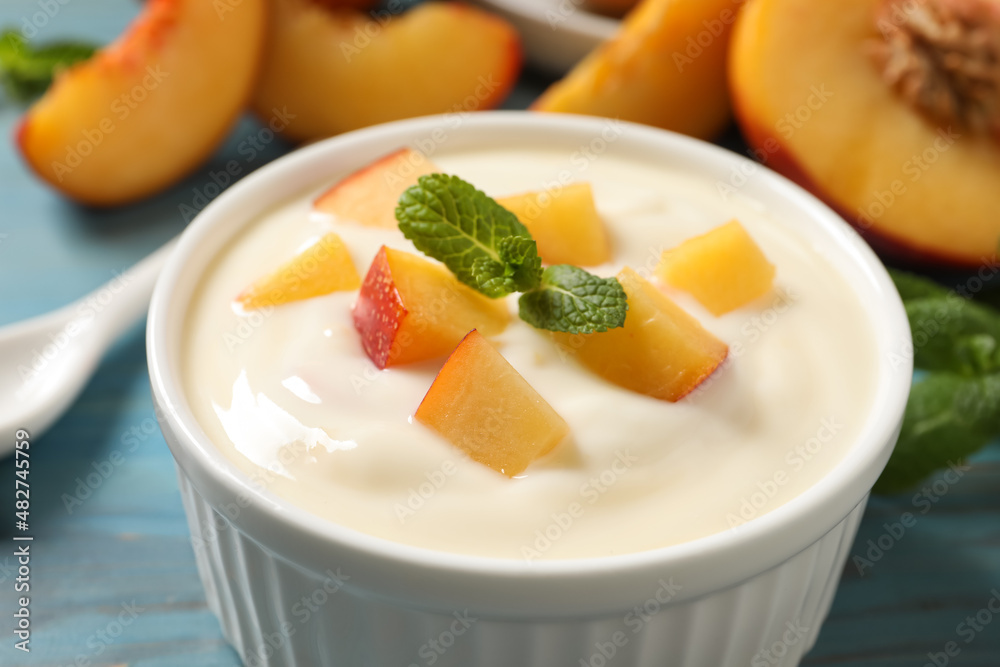 Delicious yogurt with fresh peach and mint on light blue table, closeup Delicious yogurt with fresh peach and mint on light blue table, closeup