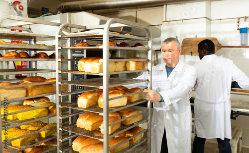 Baker pushing trolley with baked bread. High quality photo