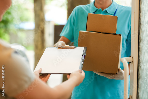 Young woman receiving parcels from courier of delivery company © Pixel-Shot