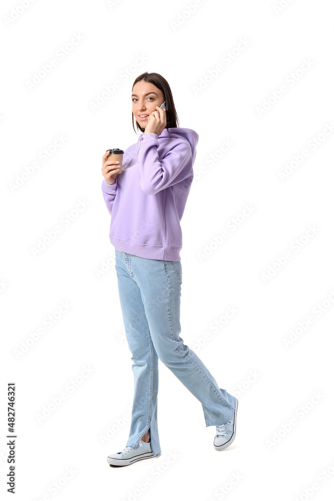 Young woman in lilac hoodie with cup of coffee talking by mobile phone on white background Young woman in lilac hoodie with cup of coffee talking by mobile phone on white background