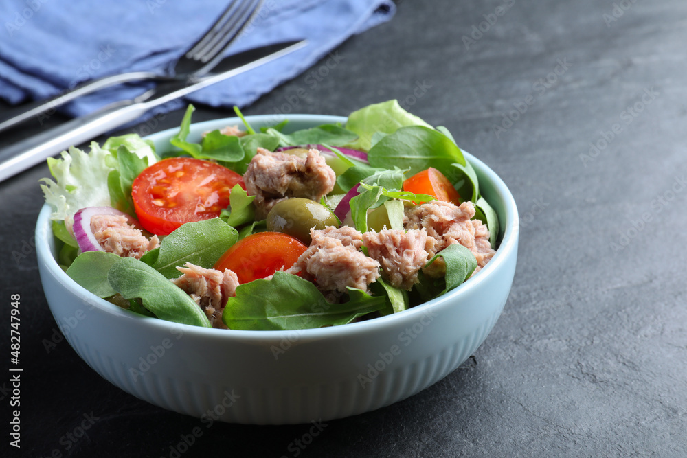 Bowl of delicious salad with canned tuna and vegetables on black table Bowl of delicious salad with canned tuna and vegetables on black table