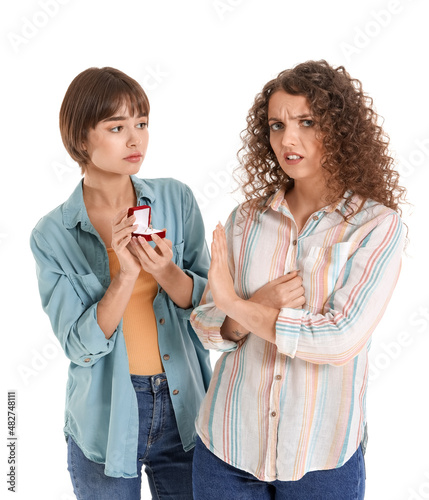 Young woman rejecting marriage proposal of her lesbian girlfriend on white background