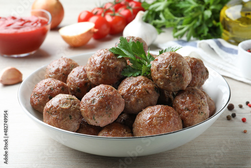 Tasty cooked meatballs with parsley on white wooden table, closeup photo