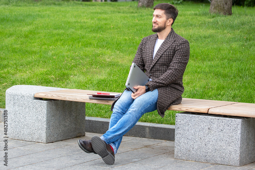 Obraz premium successful businessman resting on a city bench after a completed work project