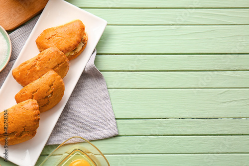 Plate of tasty sochniki with cottage cheese on green wooden background photo