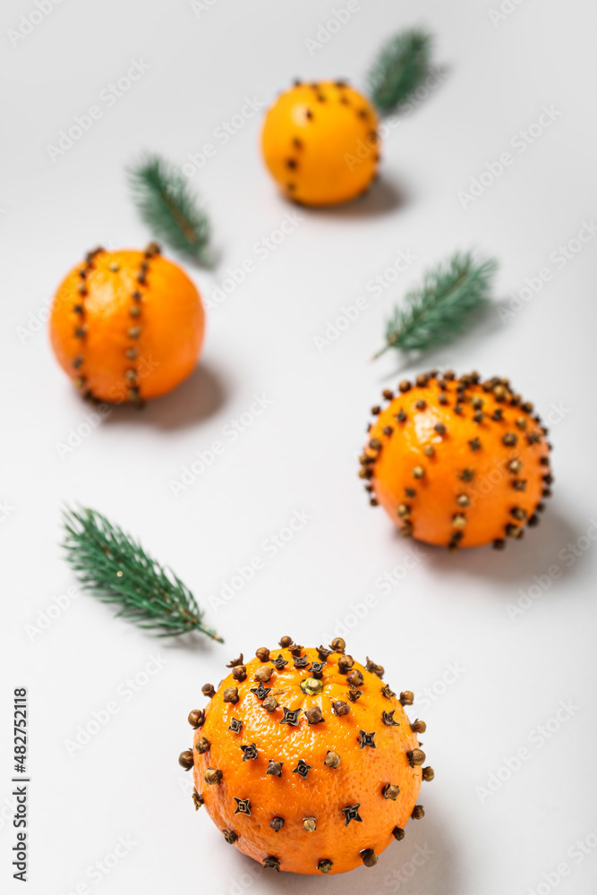 Handmade Christmas decoration made of tangerines with cloves and fir branches on light background, closeup