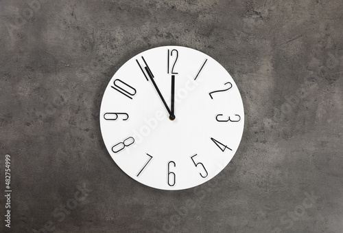 Stylish analog clock hanging on grey wall. New Year countdown