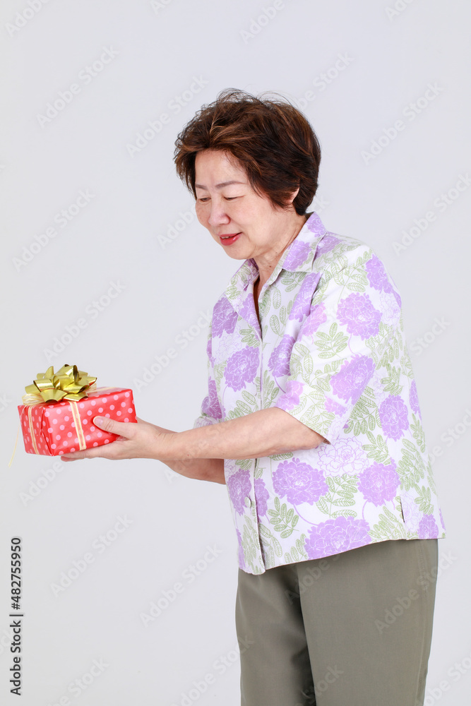 Elderly aunt, Senior Asian woman holding gift box on white background concept Elderly aunt, Senior Asian woman holding gift box on white background concept