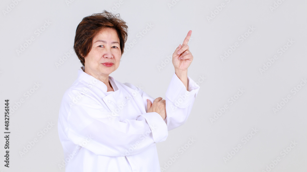 Elegant senior woman as professional chef confidently standing with arm crossed and wooden spoon and fork in restaurant kitchen Elegant senior woman as professional chef confidently standing with arm crossed and wooden spoon and fork in restaurant kitchen