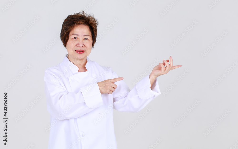 Elegant senior woman as professional chef confidently standing with arm crossed and wooden spoon and fork in restaurant kitchen Elegant senior woman as professional chef confidently standing with arm crossed and wooden spoon and fork in restaurant kitchen