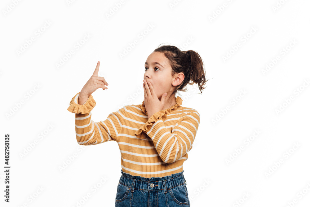 Little girl with a surprised expression while pointing up to show something on an isolated white background. Advertising and promotion concept. Little girl with a surprised expression while pointing up to show something on an isolated white background. Advertising and promotion concept.
