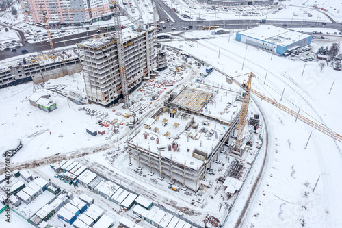 winter cityscape with construction site covered with snow. aerial overhead view.
