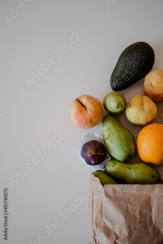 Fototapeta Naklejka Na Ścianę i Meble -  A variety of fruits in a crafted paper bag are lying on the table