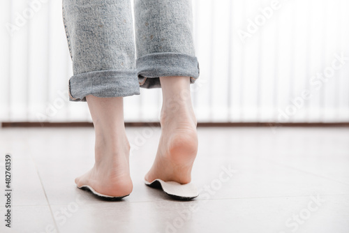 Woman fitting orthopedic insole indoors, close up. Girl holding an insole next to foot at home. Orthopedic insoles. Foot care banner. Flat Feet Correction. Treatment and prevention of foot diseases. © Maksim