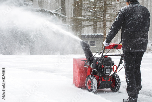 Man using snow blower machine to clear driveway at snow day. photo